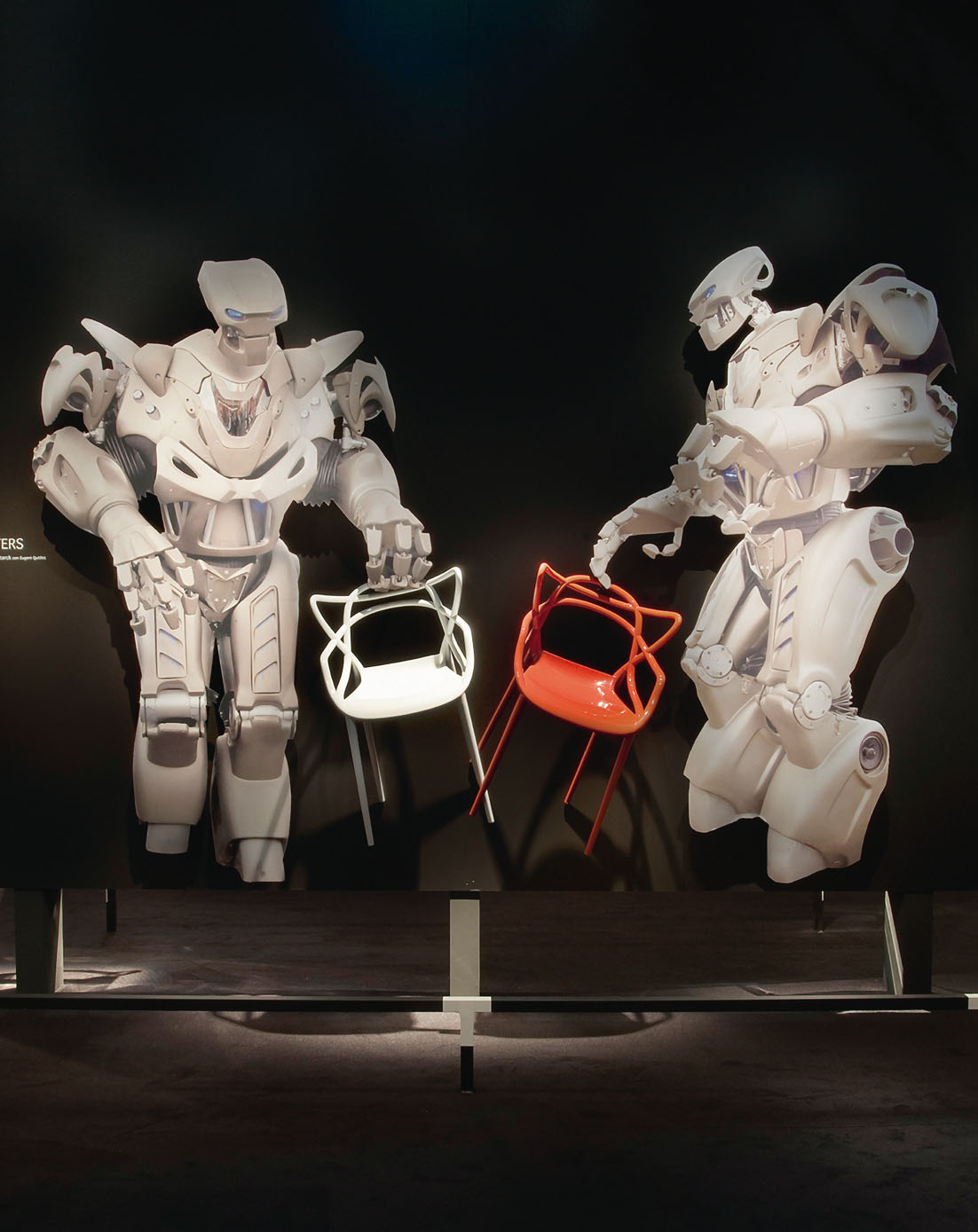 Un angolo espositivo dello stand Kartell al Salone del Mobile nel 2009 (Milano). Due robot presentano la nuova sedia Masters. / Decoration panel at the Kartell booth, Salone del Mobile, Milan, 2009. Two androids introduce the new chair Masters.