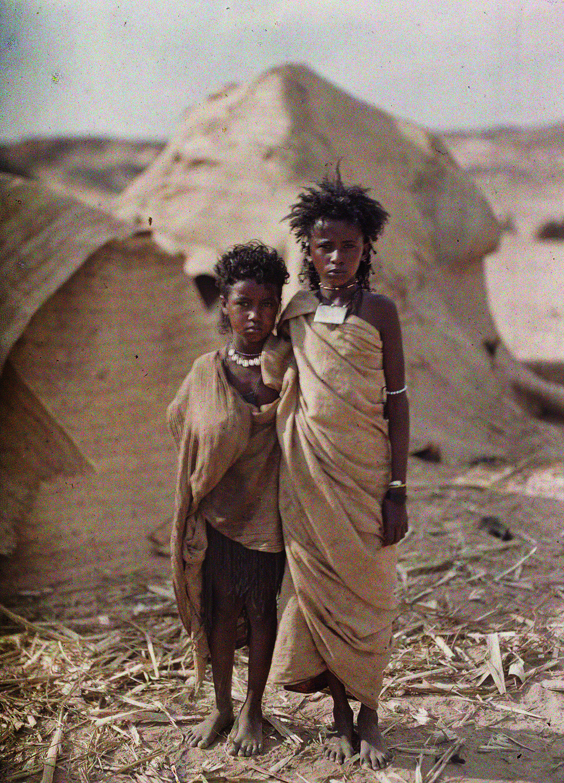 Albert Kahn, Les Archives de la Planète, Auguste Léon. Egypt, Assuan, two young Bishari- (Nubier-) women in front of their dwelling. January 1914. © Musée Albert-Kahn, Département des Hauts-de-Seine.