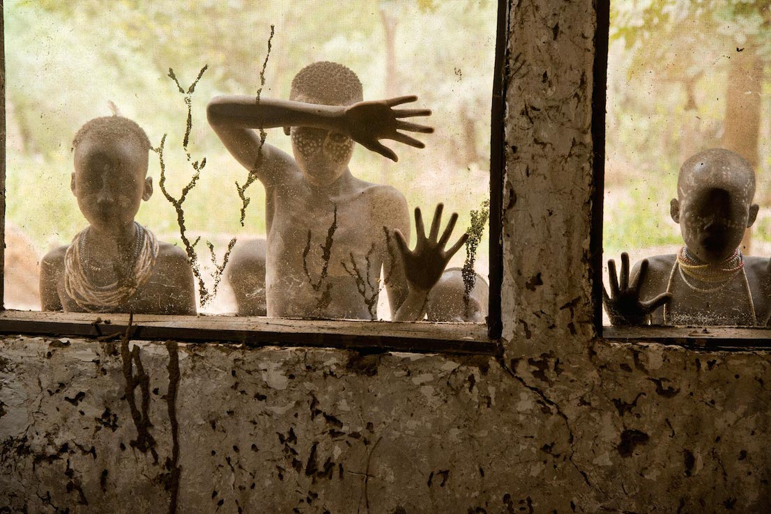 Bambini della tribù Kara che guardano attraverso le finestre, Omo Valley, Ethiopia, 2013