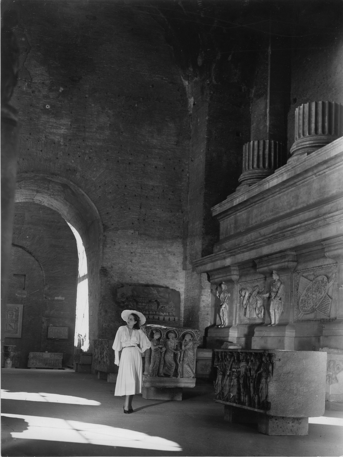 Modello Antonelli e cappello Clelia Venturi al museo delle Terme di Diocleziano, Roma, 1948. Foto Pasquale De Antonis, pubblicata in Irene Brin, La moda nella città eterna, in “I Tessili Nuovi”, estate 1948. Courtesy Archivio De Antonis, Roma.