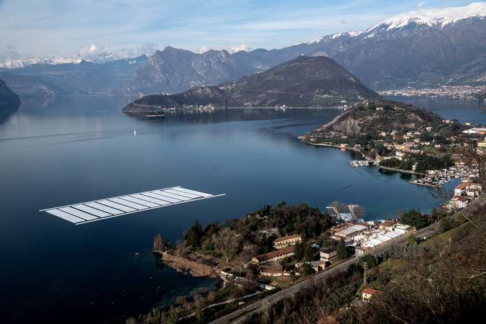 Vista aerea del cantiere di costruzione del progetto sulla penisola di Montecolino (a sinistra) e dell'area di parcheggio per le trenta sezioni di 100 x 16 metri sul Lago d'Iseo (a destra), Aprile 2016.