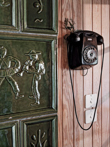 Particolare dell'interno con la decorazione a formelle di terracotta e il telefono originale. Foto: © Marcello Mariana.