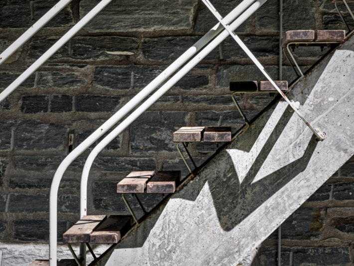 Details of the external staircase with a springboard structure made of a reinforced-concrete beam with a variable cross section, thirteen wooden treads resting on two continuous metal strips and handrails of white metal tubing. Photo: © Marcello Mariana.